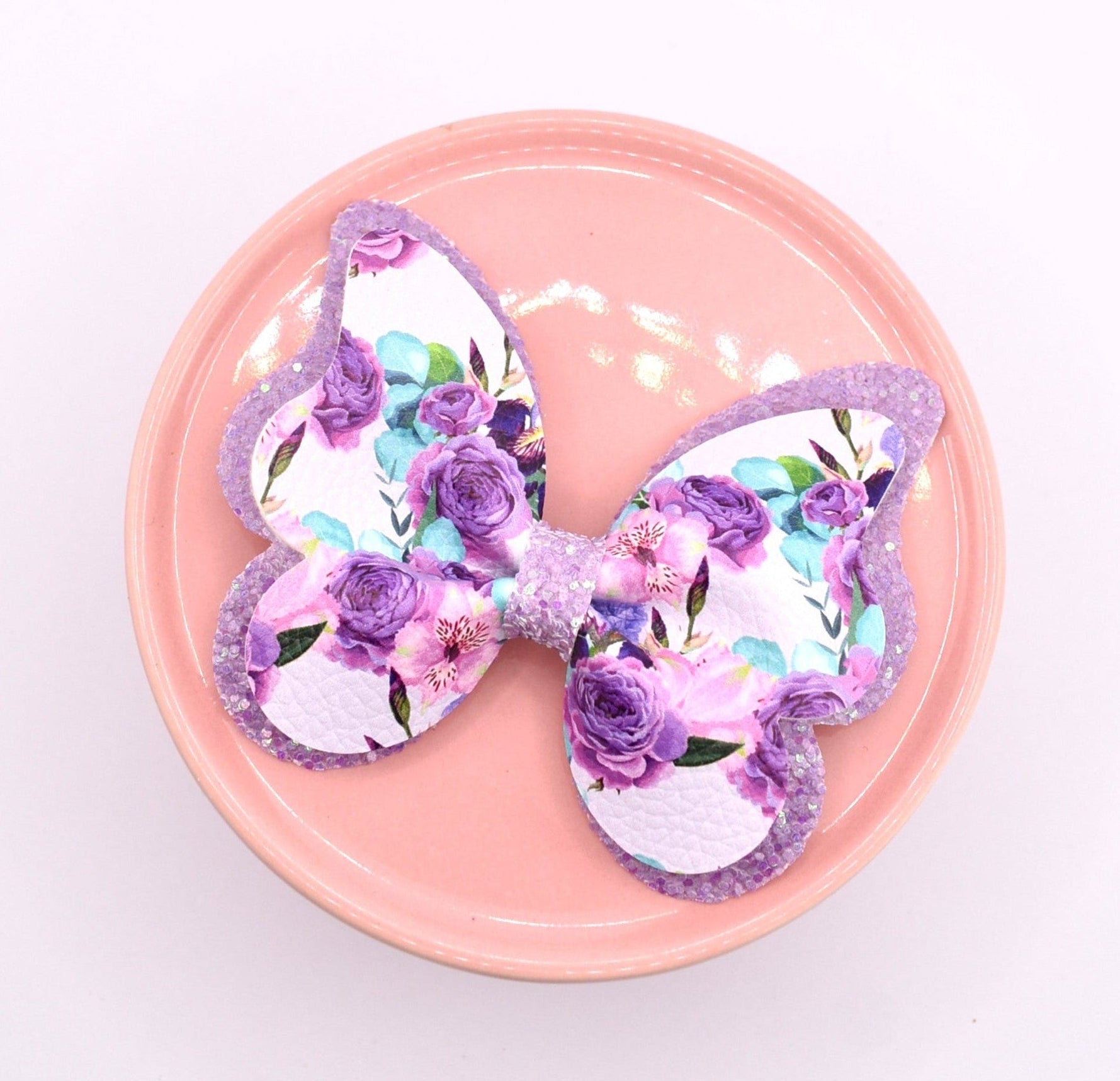 Butterfly-shaped hair bow with floral design on a pink plate