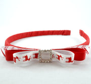 A red and white Christmas-themed headband with a rhinestone buckle in the center, featuring a reindeer design on the white ribbon.